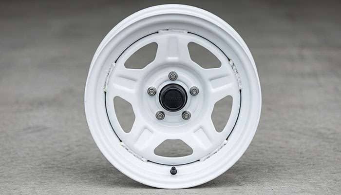 Close-up view of a steel trailer wheel showing the stamped construction with painted finish center disc welded to the outer barrel and lug holes