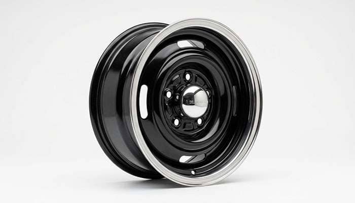Black steel wheel fitted with a chrome dog dish center cap and trim ring on a clean white seamless studio backdrop