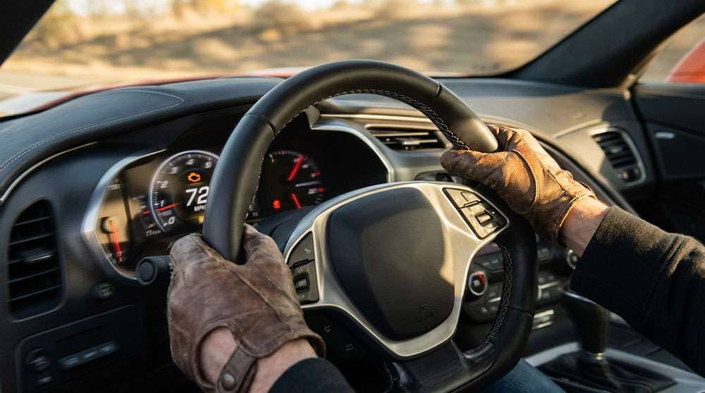 Driver gripping a vibrating steering wheel showing visible motion blur with informational text about steering wheel shake causes and fixes