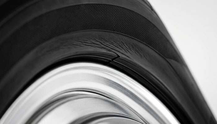 Close-up of a stretched tire bead seated at an angle against an exposed polished wheel lip showing the sidewall pulled tight