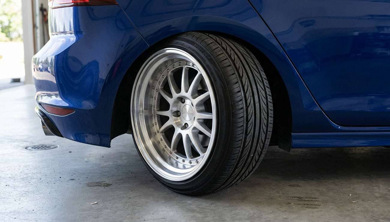 Low profile tire stretched onto a wide aftermarket wheel with the sidewall angled outward and the rim lip fully exposed