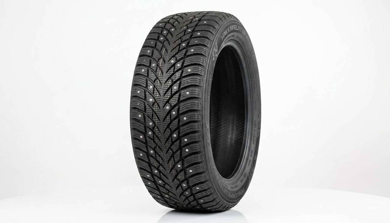 Studded winter tire with rows of carbide studs set in the tread blocks, shown at a 45-degree angle