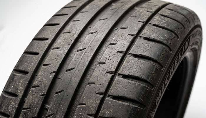 Summer tire tread blocks showing fine cold cracking at the block corners and groove bases