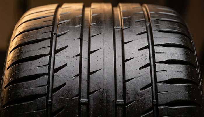 Close-up of summer tire tread pattern showing solid center rib and large contact patch for maximum grip