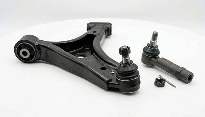 Close-up of front suspension components including a control arm, ball joint, and tie rod end displayed on a clean white studio backdrop