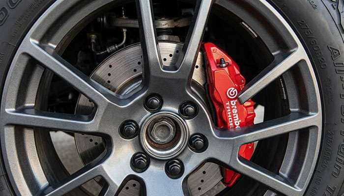 Large front brake caliper on a full-size SUV hub showing clearance to the inside of a 20-inch wheel's spokes
