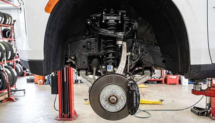 Leveling spacer installed on the front strut of a Chevy Tahoe on a shop lift