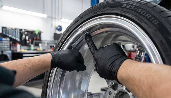 Technician applying adhesive wheel weight to the inner surface of an aluminum alloy wheel rim