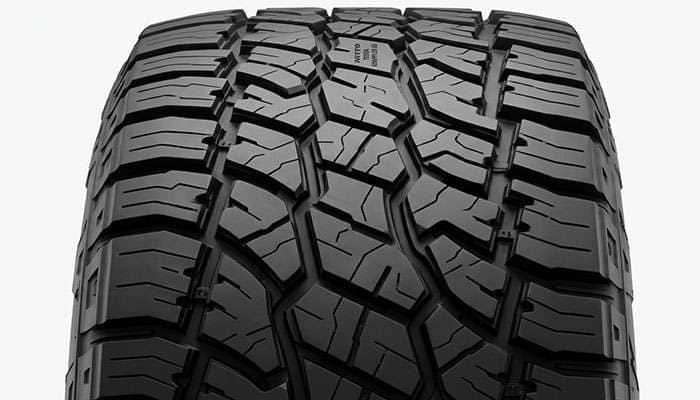 Close-up of the Nitto Terra Grappler G2 tread pattern showing full-depth sipes and staggered shoulder lugs