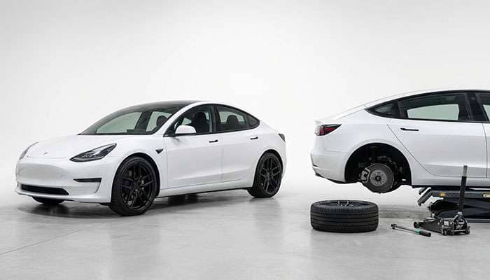 Side-by-side image of a white Tesla with black forged wheels and another Tesla having a wheel replaced with a tire on the ground.