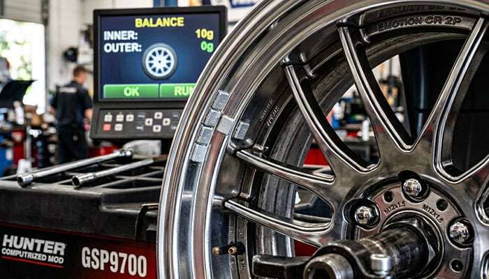 Close-up of a wheel balancing machine with counterweights applied to a car rim