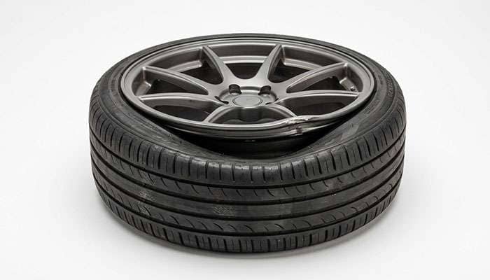 Deflated low profile tire with its bead pulled away from the edge of an aftermarket wheel after unseating
