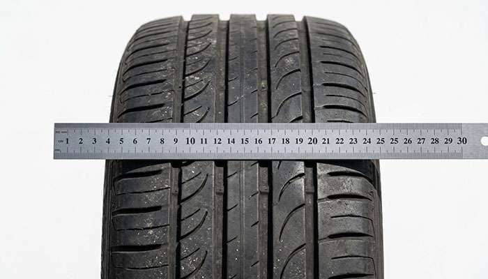 close-up of a raised high spot in a tire tread face with a straightedge laid across the tread showing the deformation