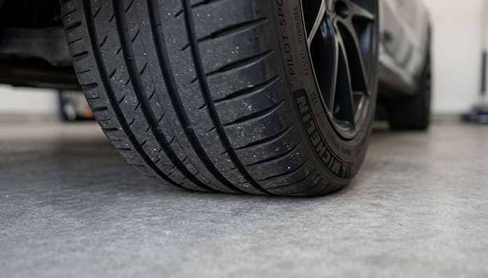 Close-up view of a car tire contact patch resting on a concrete garage floor showing slight deformation