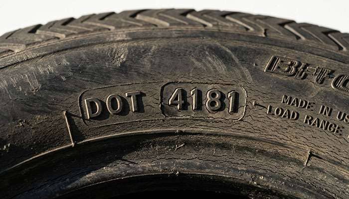 Close-up of a four-digit DOT date code on an older classic car tire sidewall with light weather cracking