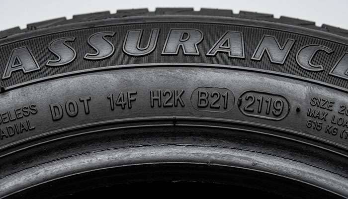 Close-up of a tire sidewall showing the DOT identification number and four-digit date code stamping