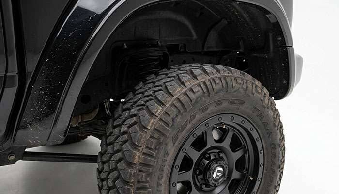 Close-up of off-road tire inside truck wheel well showing fender clearance gap