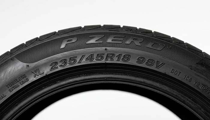 Close-up of a tire sidewall showing the size, load index, and speed rating against a clean white studio backdrop