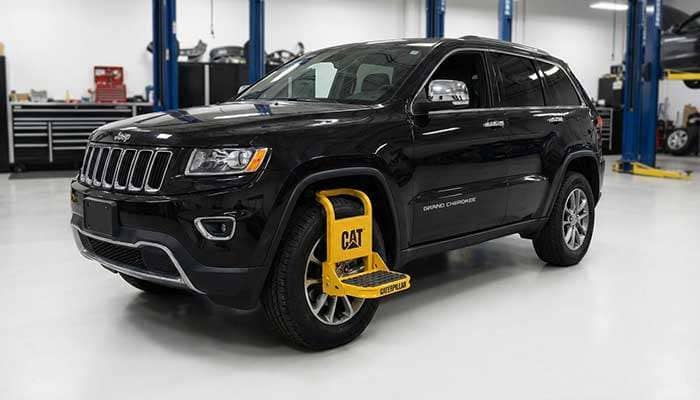 Yellow CAT tire-mounted work service step attached to the rear tire of a black Jeep SUV in a garage