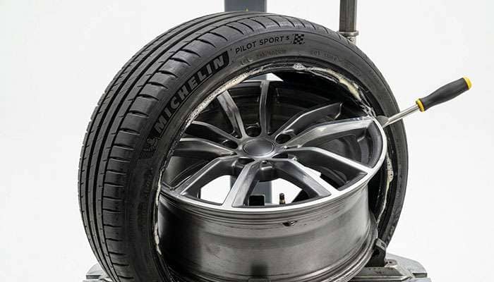 A tire being mounted onto a wheel rim on a clean white studio backdrop
