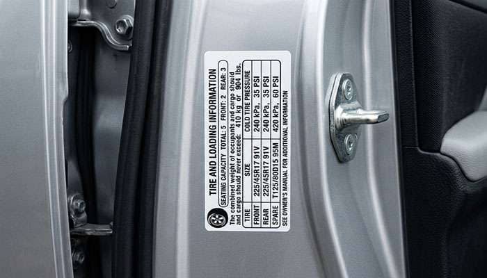 Driver door jamb tire placard showing tire size, load index and cold inflation pressure