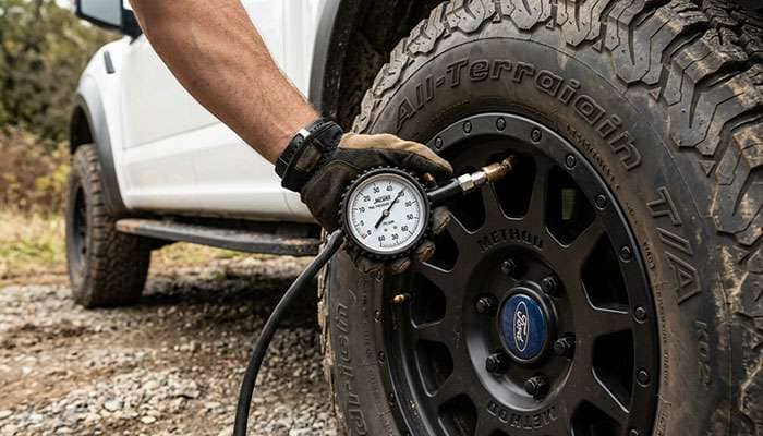 Tire pressure gauge checking inflation on a light truck tire mounted on a pickup