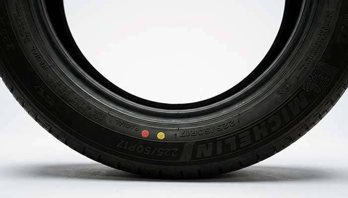 Close-up of a tire showing red and yellow dots with text asking their meaning on the tire sidewall