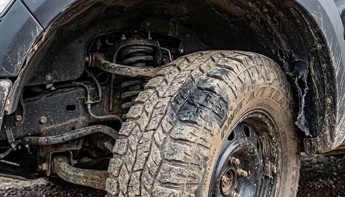 Close view of an oversized truck tire contacting the plastic fender liner at full steering lock, showing scuff marks on the tread shoulder