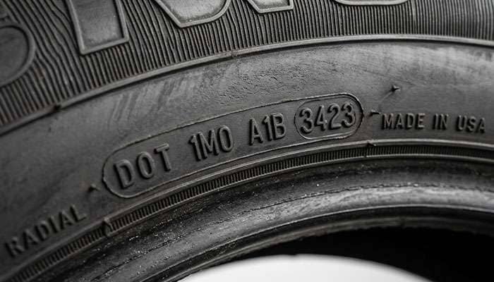 Close-up of a tire sidewall showing the raised DOT tire identification number and plant code