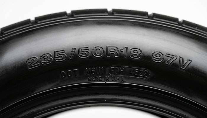 Close-up of a tire sidewall showing the size, load index and speed rating markings