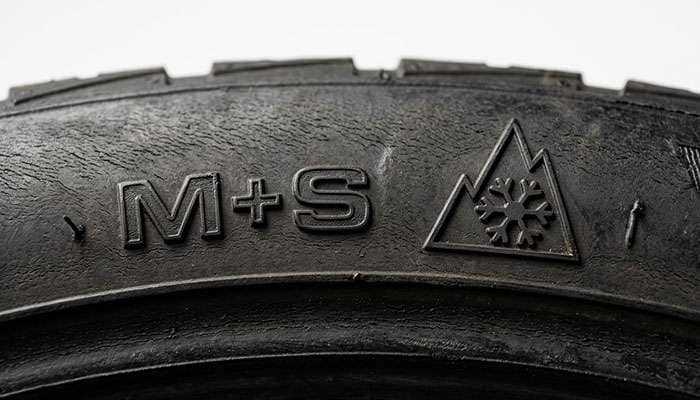 Close-up comparison of tire sidewall showing M+S marking next to Three-Peak Mountain Snowflake symbol
