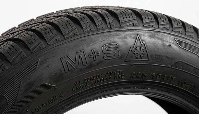 Close-up of a tire sidewall showing the M+S mud and snow marking and the three-peak mountain snowflake symbol