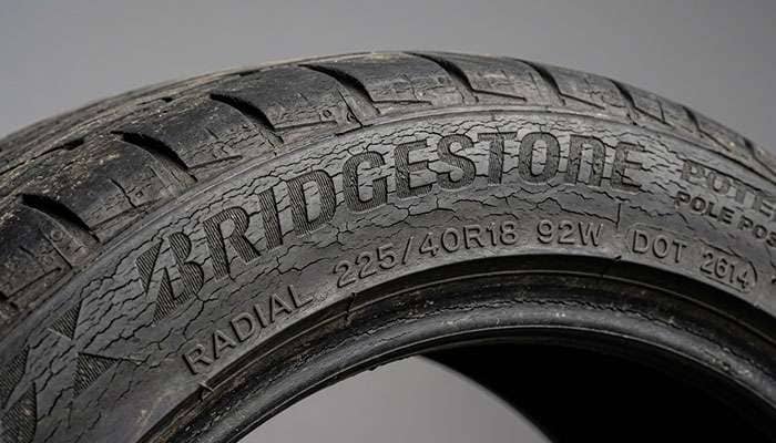 Close-up of a car tire sidewall showing early ozone cracking damage from long-term inactivity and exposure