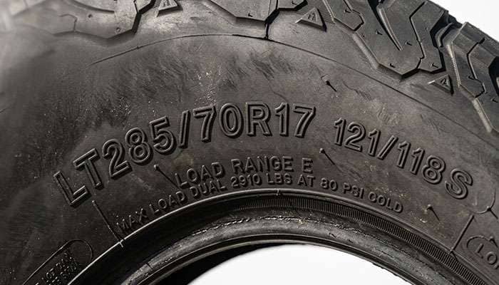 Close-up of the LT235/85R16 size marking and load index stamped into a light truck tire sidewall