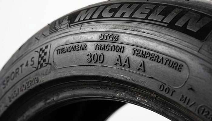 Close-up of a tire sidewall showing the UTQG treadwear, traction, and temperature ratings