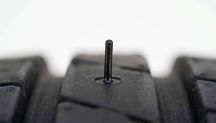 Macro close-up of a single rubber vent spew strand on a new tire