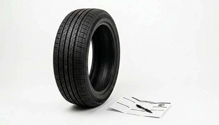 Tire beside a folded warranty document and pen on a clean studio background