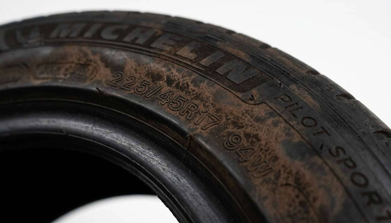 Close-up of a tire sidewall showing brown blooming discoloration