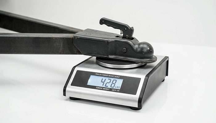 Tongue weight scale being used to measure the downward force of a loaded trailer on a clean white studio surface