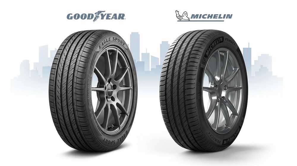 Side-by-side comparison of Goodyear and Michelin tires with their logos and a city skyline background