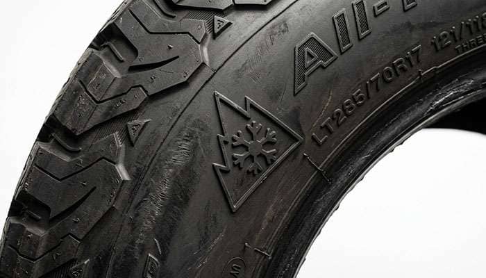 Toyo Open Country A/T III sidewall showing the Three-Peak Mountain Snowflake severe snow symbol on a clean studio backdrop