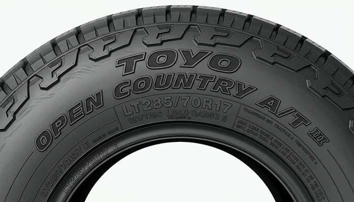 Toyo Open Country A/T III LT-metric sidewall showing load range and size markings on a clean studio backdrop