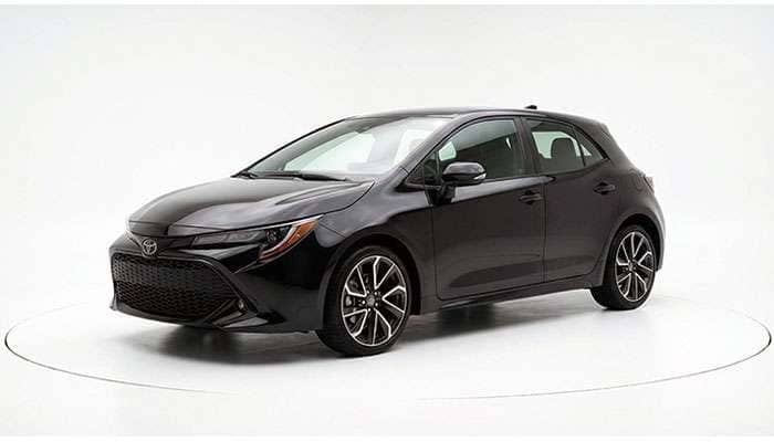Black 2026 Toyota Corolla Hatchback shown from front-side angle on white background for comparison with 2025 Volkswagen Taos