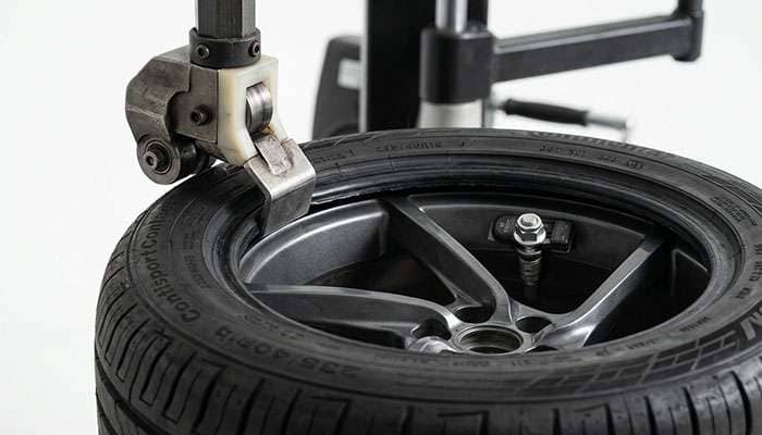 Tire changer mount head working a tire bead over an alloy wheel with the TPMS sensor valve stem positioned away from the head