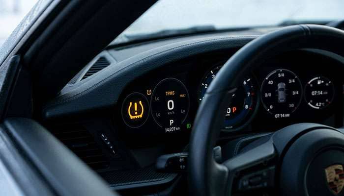 Vehicle dashboard with TPMS tire pressure warning light illuminated showing low pressure alert