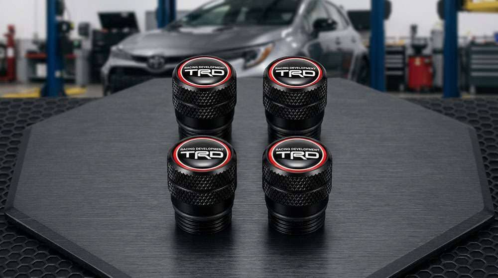 Set of four black TRD Racing Development tire valve stem caps with red, white, and black logo tops for cars