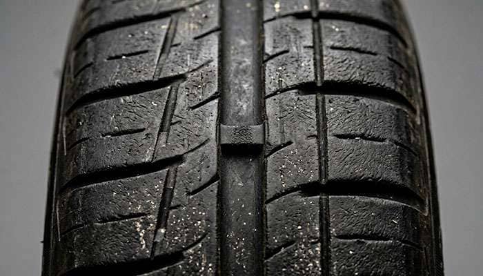 Close-up of tire tread wear indicator bar between tread grooves showing replacement threshold