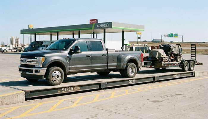 Pickup truck and trailer positioned on a certified multi-platform truck scale at a highway truck stop