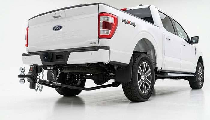 Rear of a pickup truck showing the hitch receiver and ball positioned behind the rear axle, illustrating the lever arm created by tongue weight