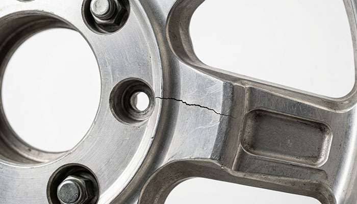 Stress crack in aluminum truck wheel spoke near hub showing metal fatigue damage